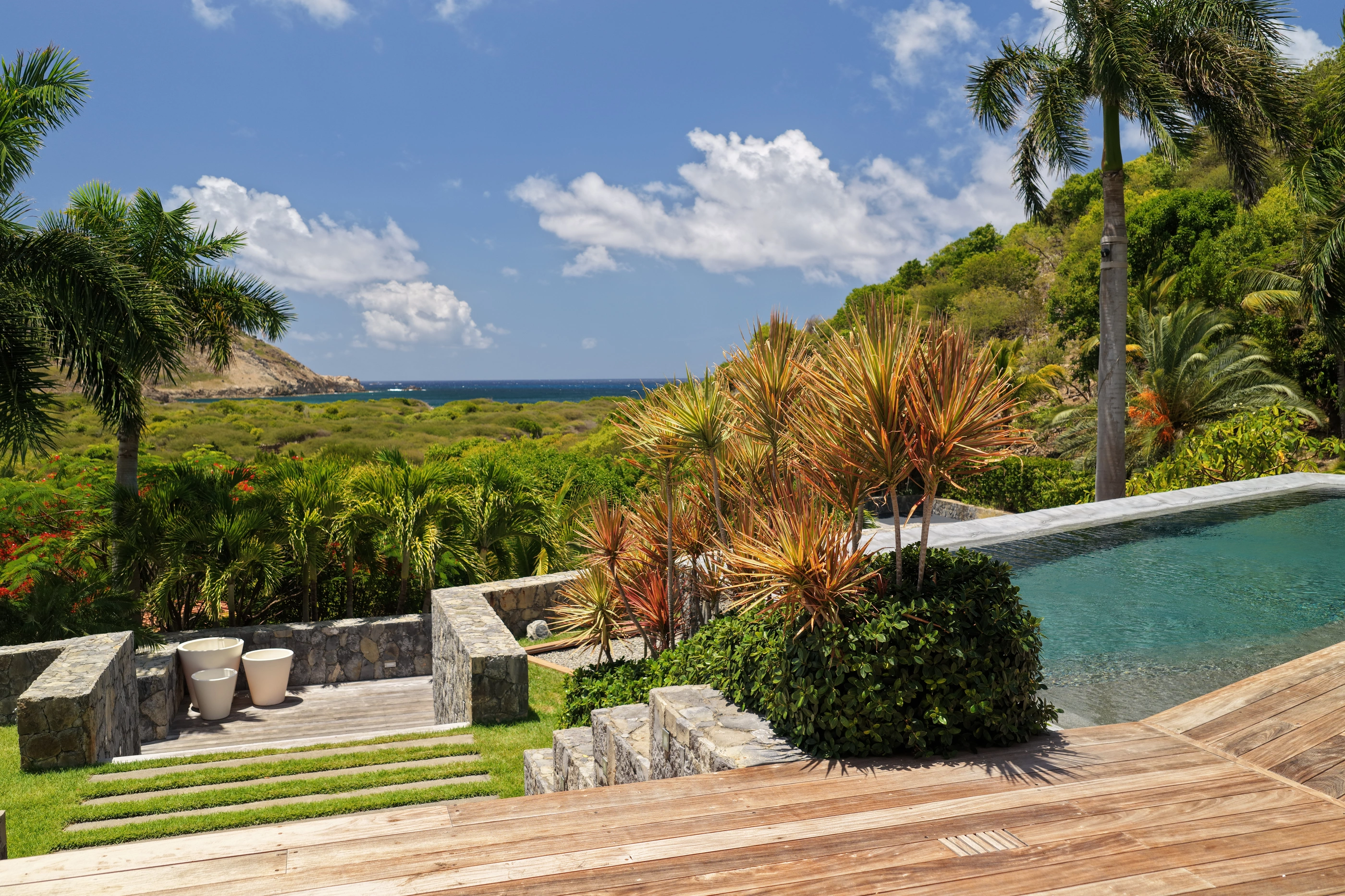 From the pool deck over the vegetation to the bay and the headland