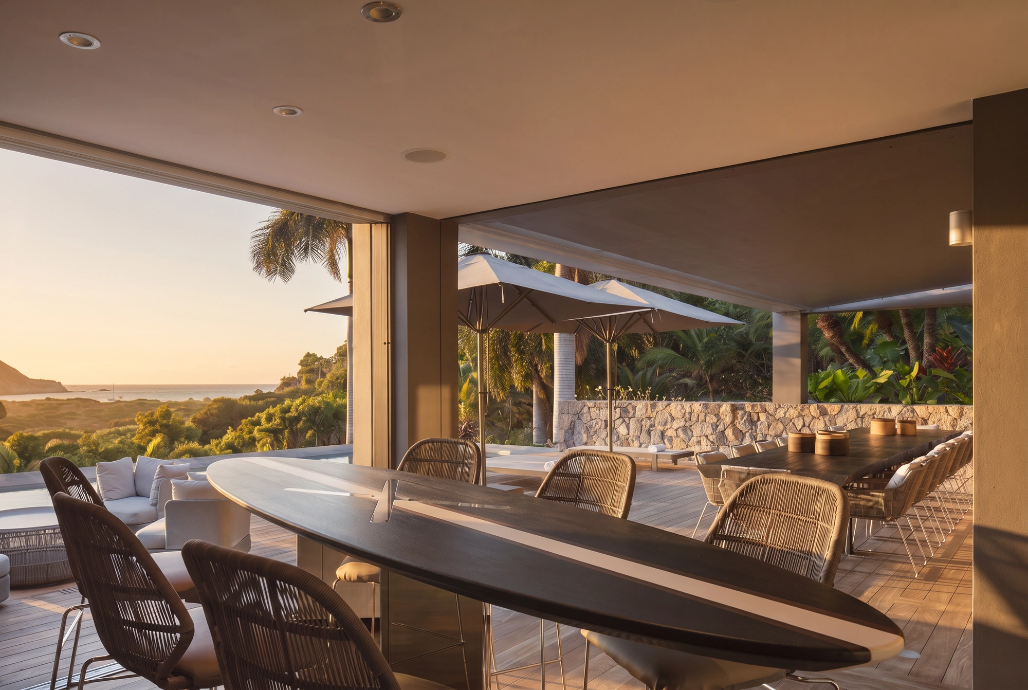 The covered terrace at sunset, the long table set, the sea beyond
