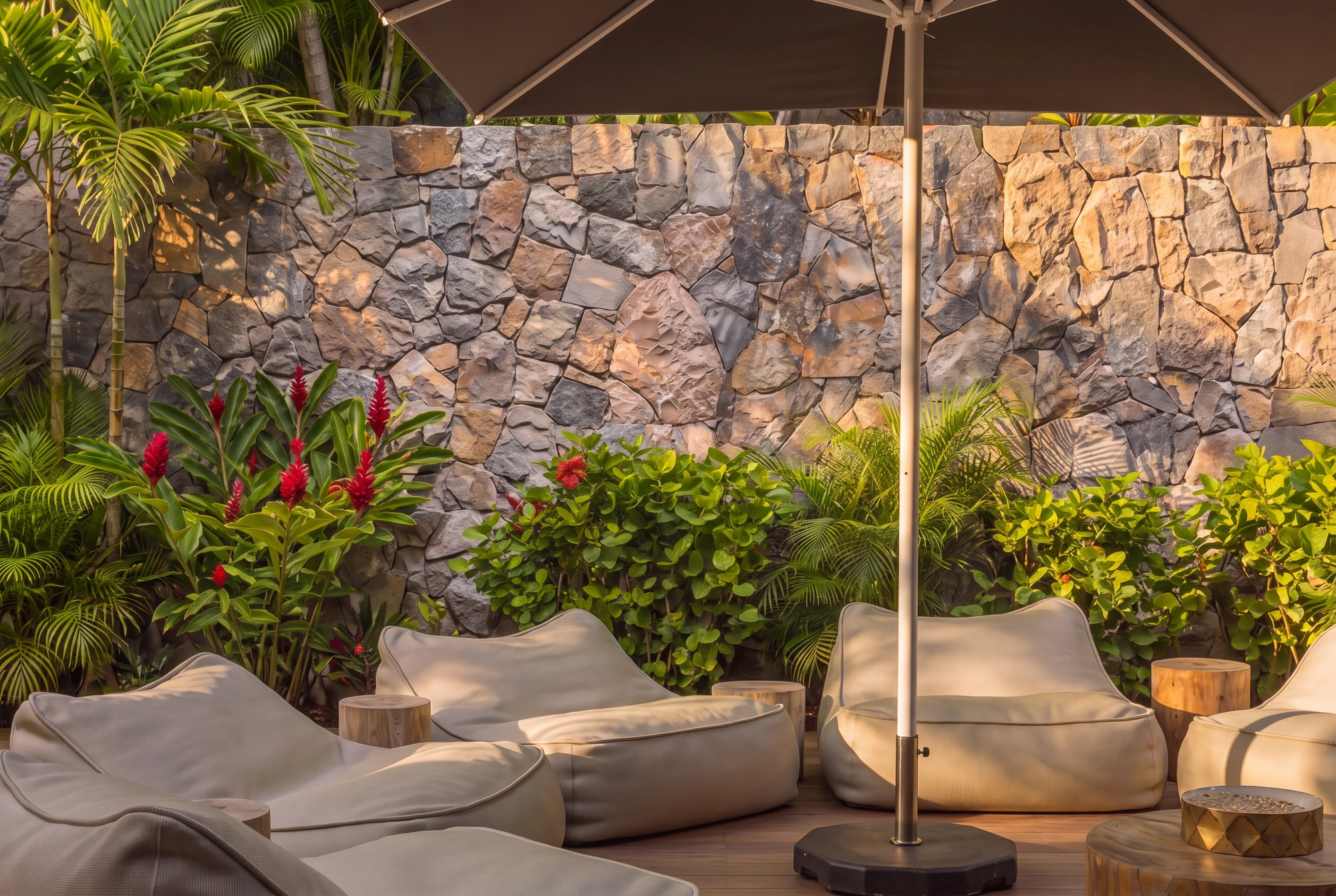 Beanbags under a parasol against the hand-laid stone wall, red ginger in the planting