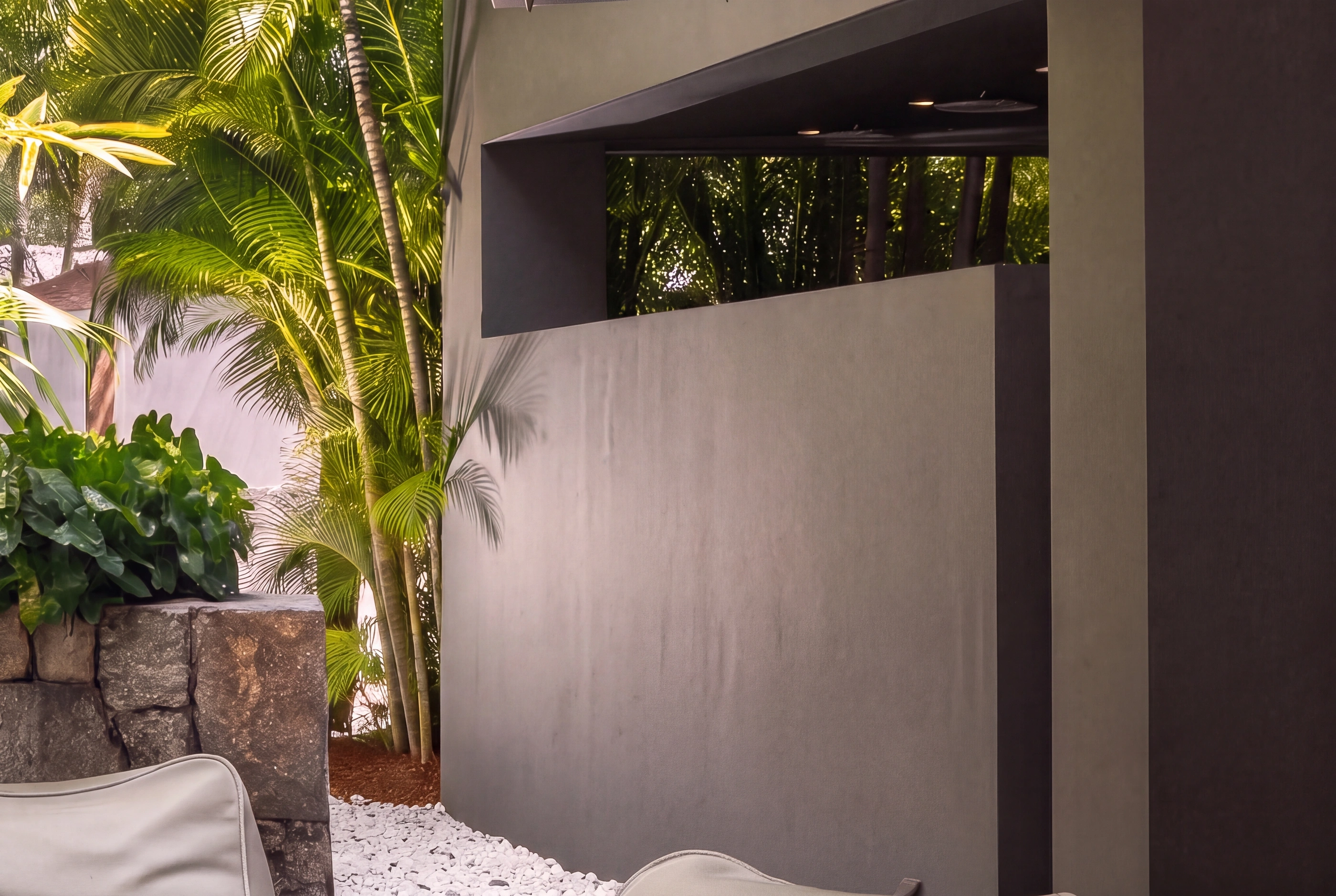 A charcoal wall meeting the stone and the vegetation