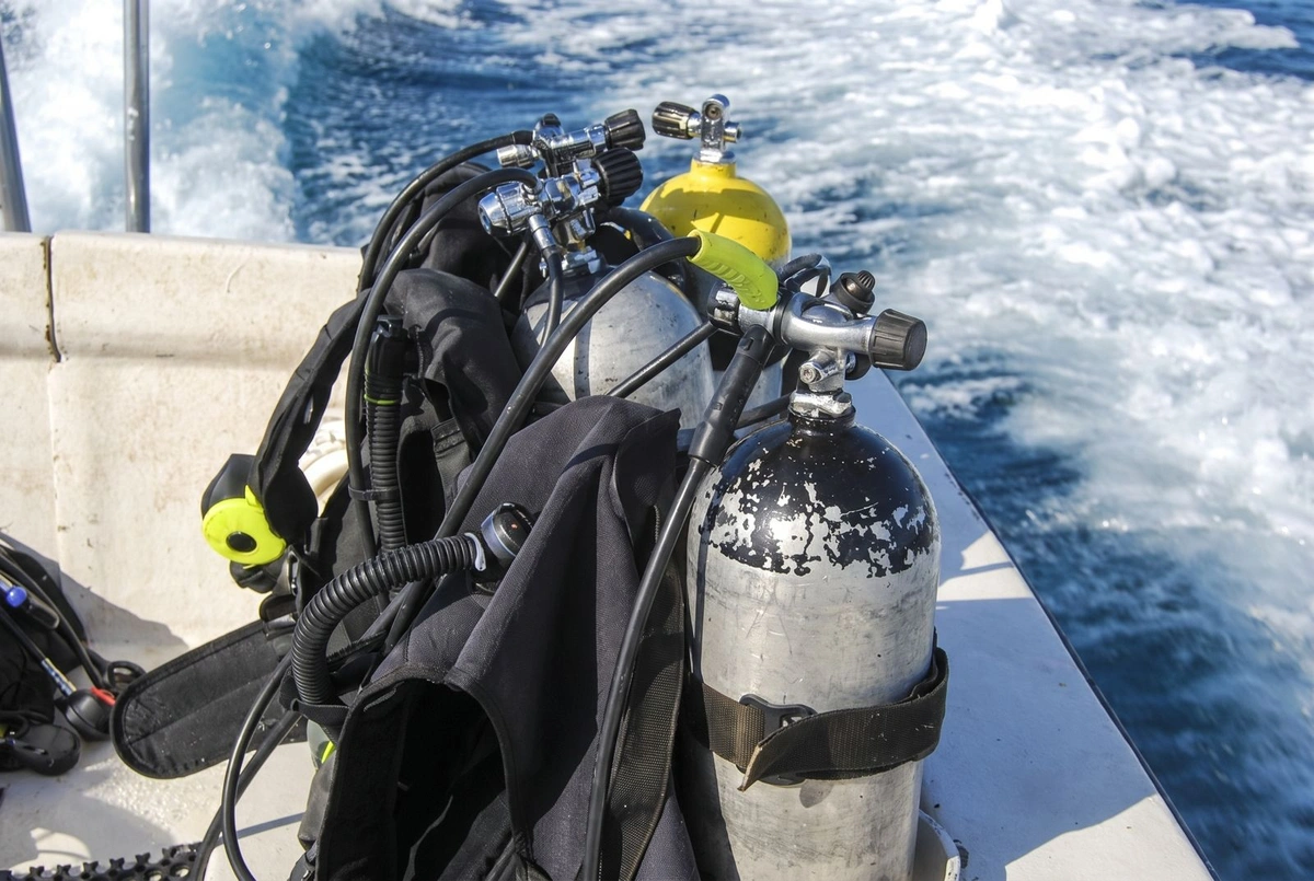 Dive tanks and jackets on a boat's deck, the wake behind